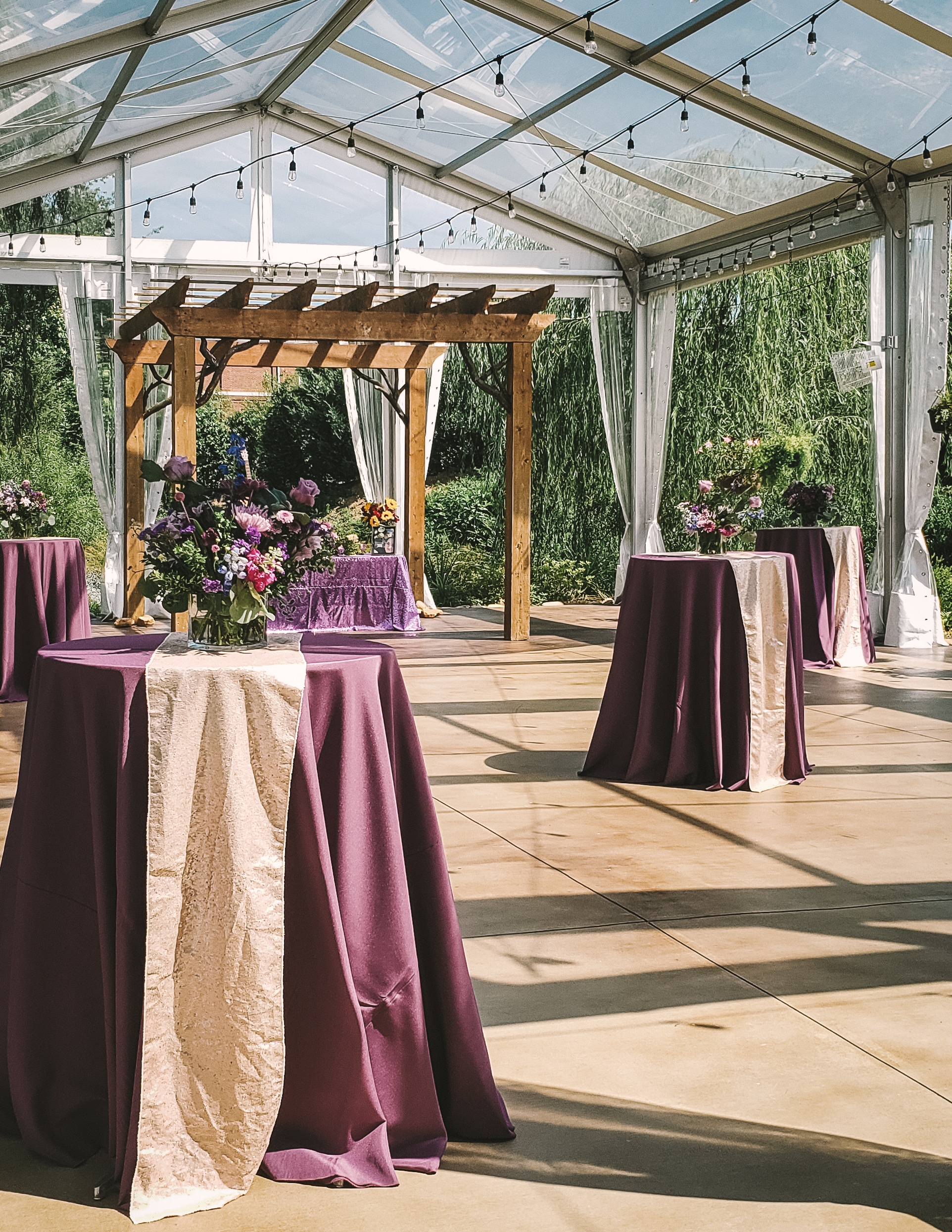 tables with purple cloths and flowers in a white tent